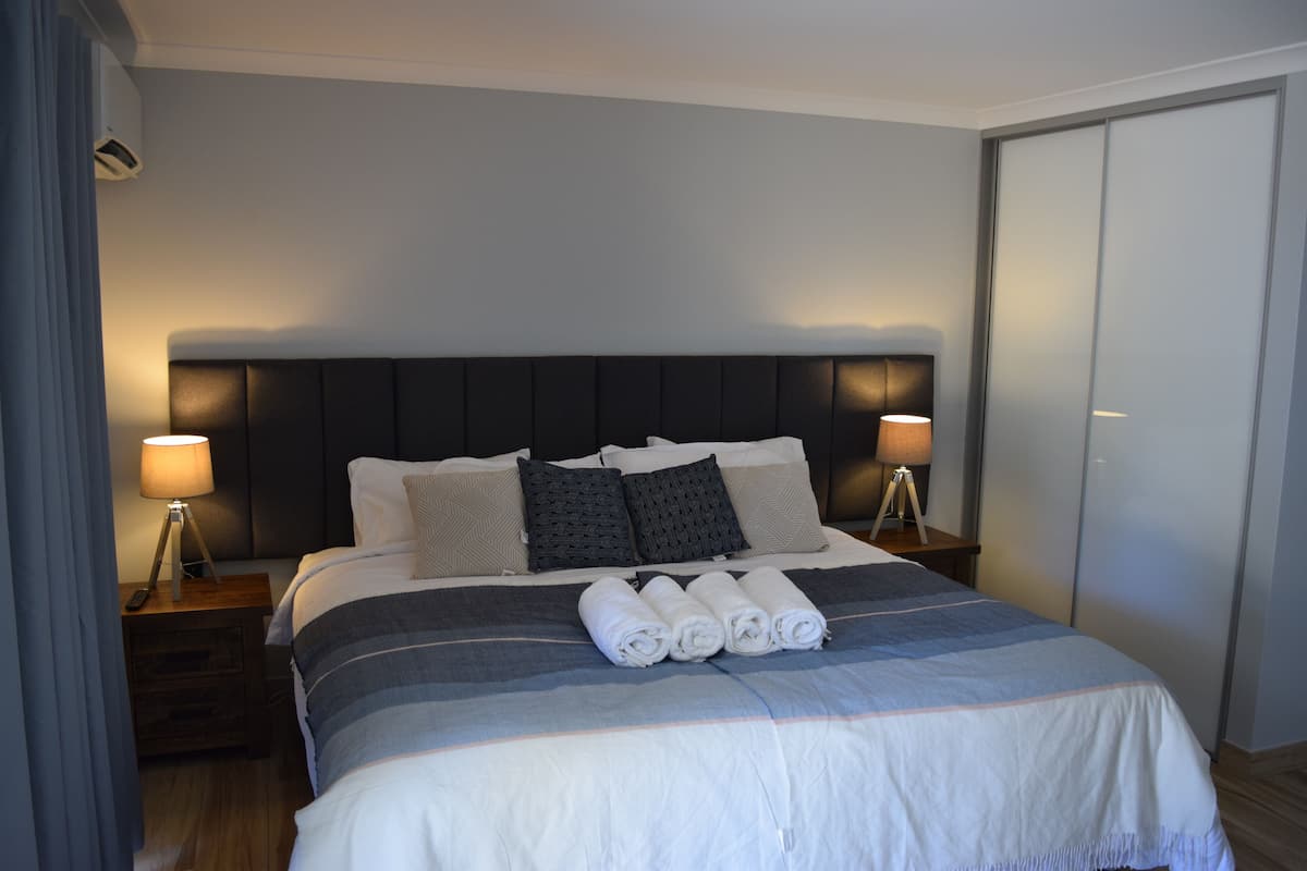 A neatly made bed with a striped bedspread, two bedside lamps, and a dark headboard.