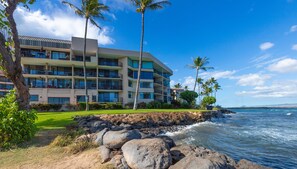 A beachfront hotel with multiple balconies, a well-maintained lawn, and a view of the ocean. - Magnificent....Marvelous....Open Dates...Wonderful Waves! (Village of Ma'alaea)
