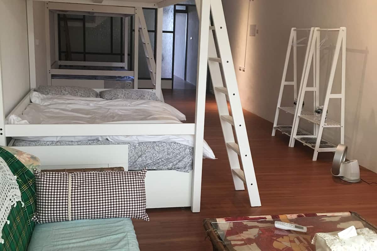 Une chambre avec un lit superposé, une échelle, une petite table avec une télécommande et une nappe décorative.