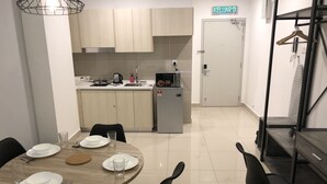 Een moderne keuken met lichte houten kastjes, een roestvrijstalen spoelbak en een koelkast. Er staat een eettafel met stoelen en borden gedekt voor een maaltijd.
