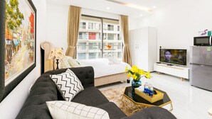 A modern living room with a bed, sofa, TV, and a dining area with a table and chairs.