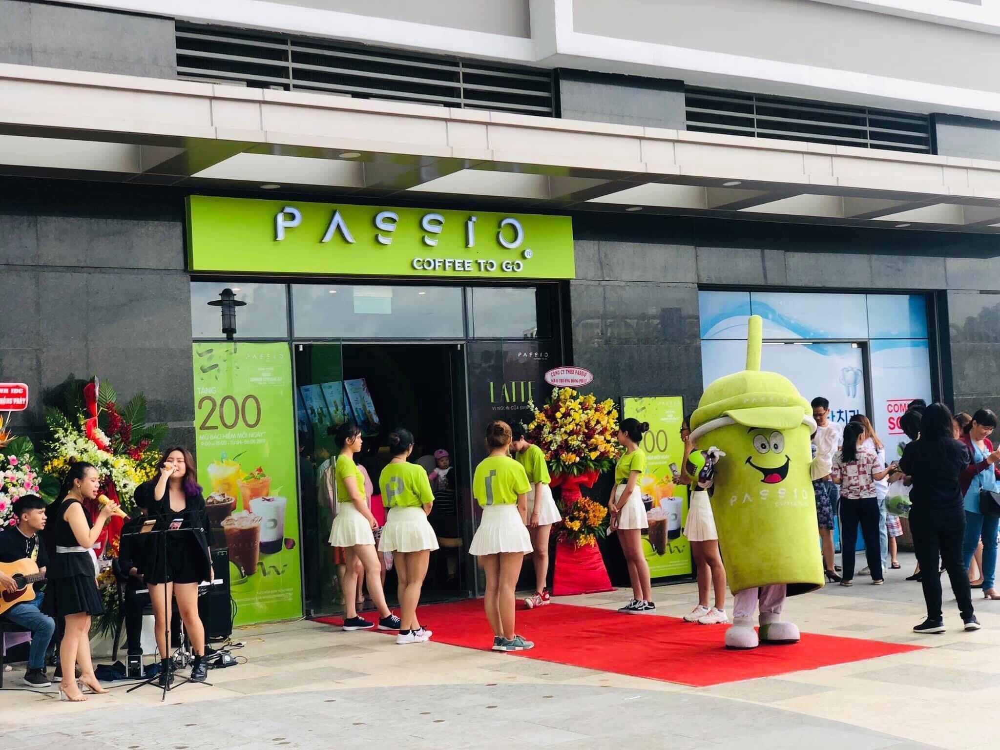 A coffee shop entrance with a green sign, a red carpet, and a mascot.