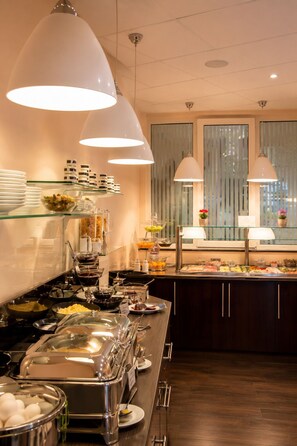 Montaje tipo buffet con múltiples estaciones de servicio, cristalería y una variedad de alimentos.