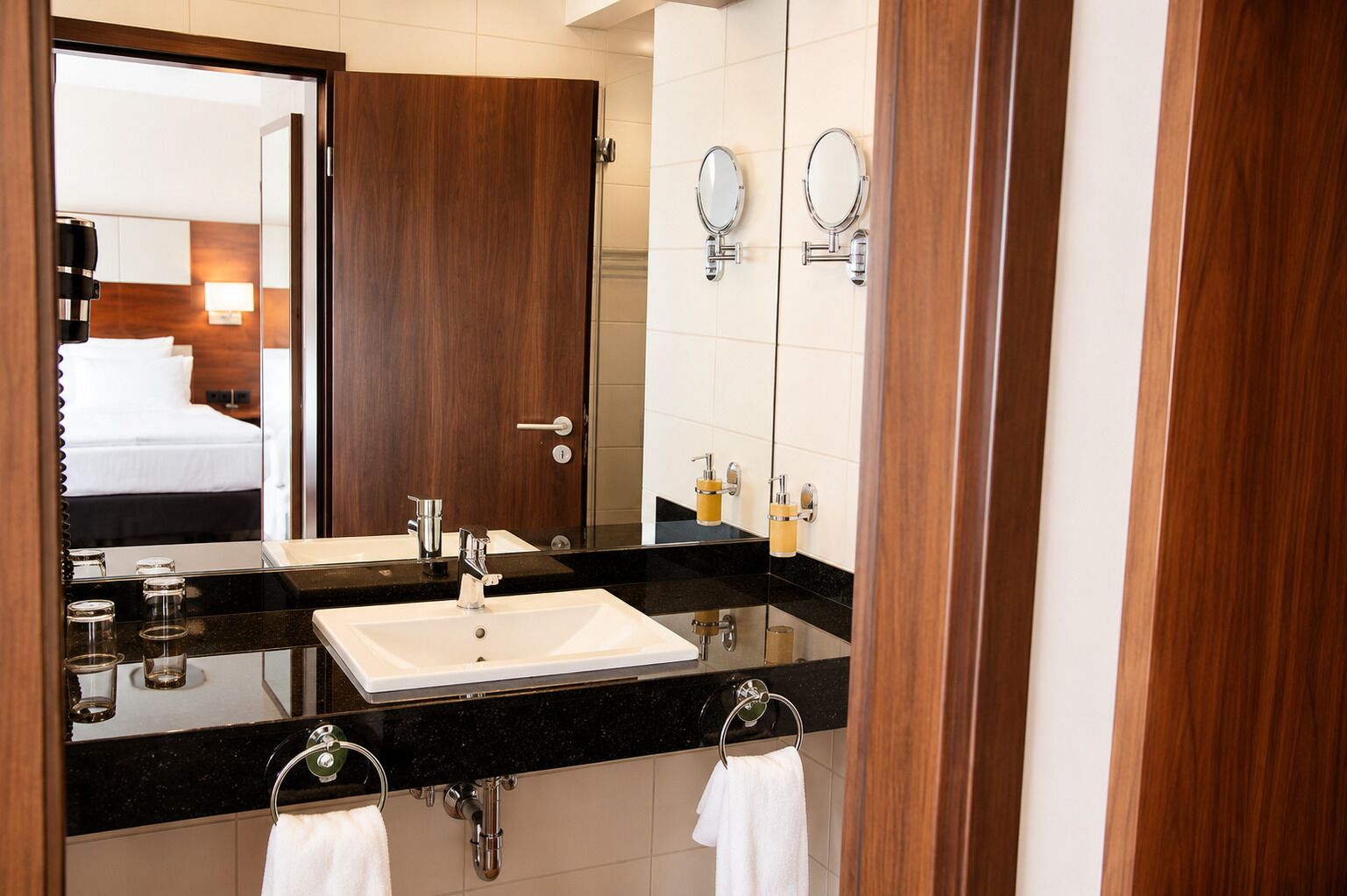 A hotel bathroom with a large mirror, a sink, and a towel rack.