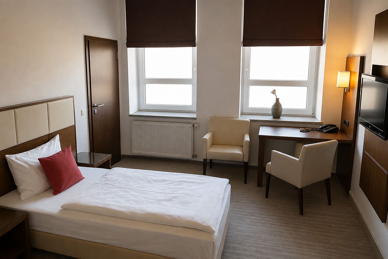 Habitación de hotel con cama, dos sillas, escritorio, televisor y ventana con vistas.