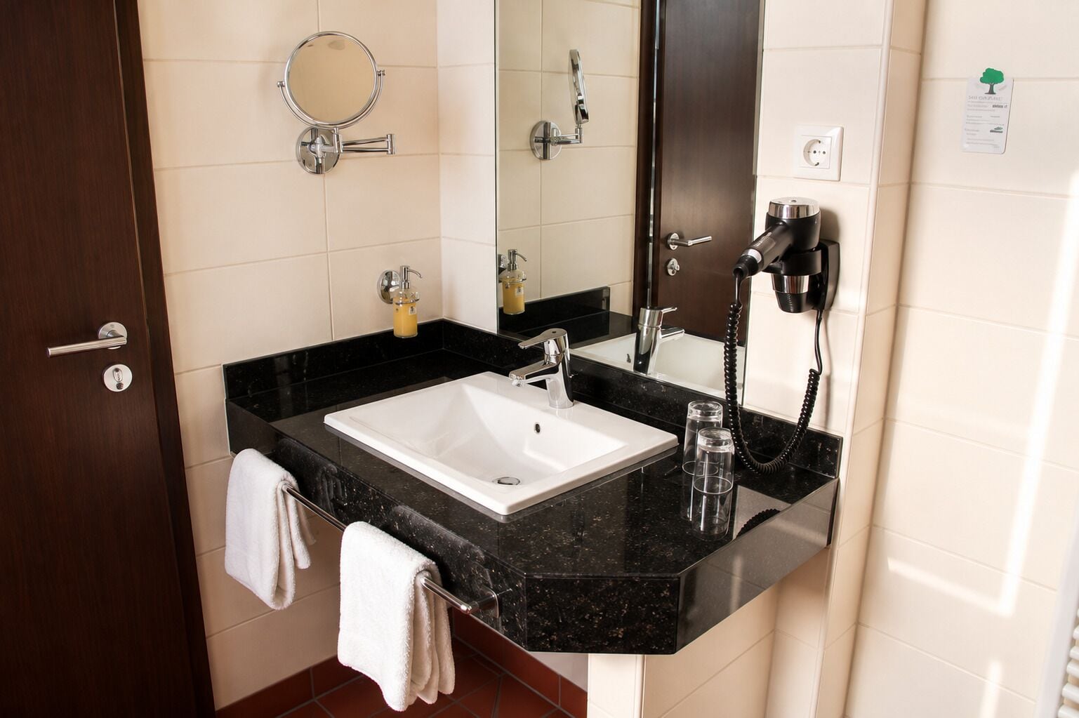 A bathroom with a white sink, a mirror, a hairdryer, and a towel rack.