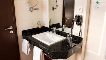 A bathroom with a white sink, a mirror, a hairdryer, and a towel rack.