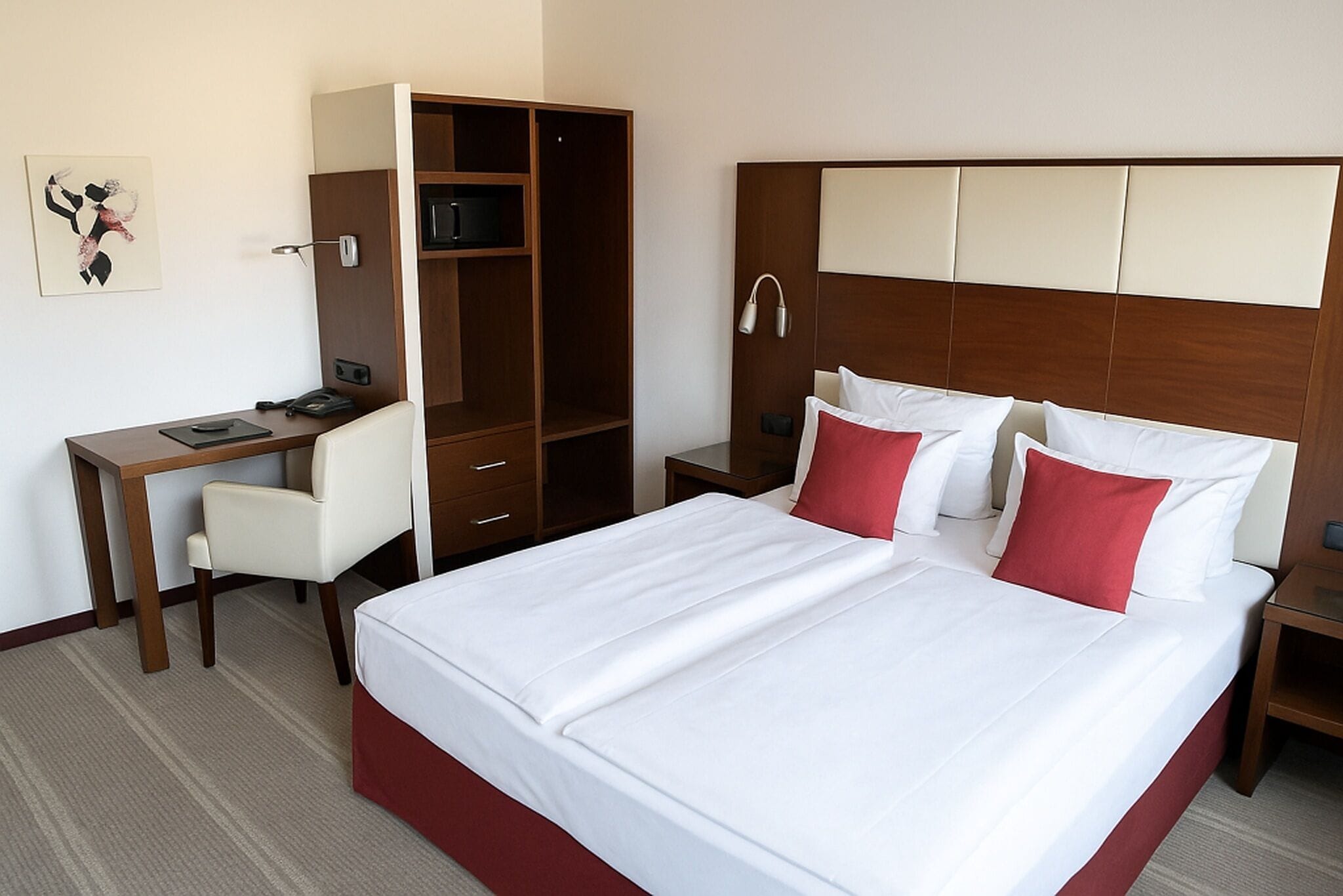 A hotel room with a bed, a desk, and a wardrobe.