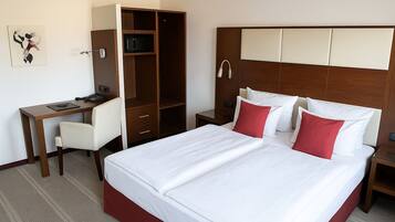 A hotel room with a bed, a desk, and a wardrobe.