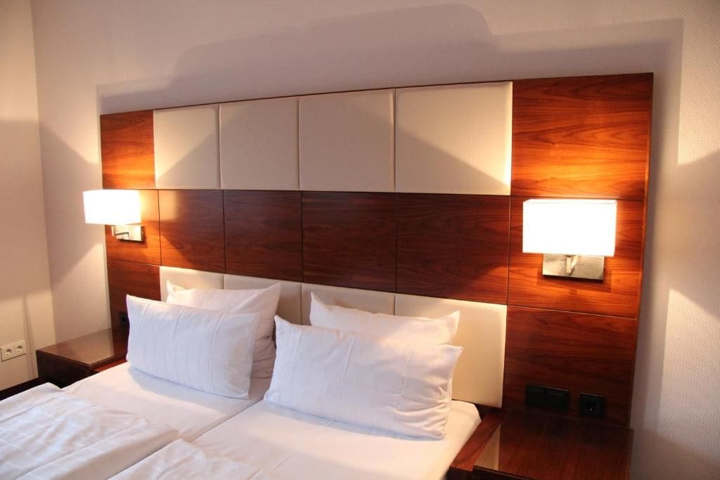 Una habitación de hotel con una cama grande, dos lámparas de noche y un cabecero de madera.