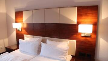 Una habitación de hotel con una cama grande, dos lámparas de noche y un cabecero de madera.