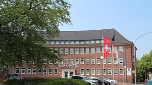 Un edificio de ladrillo rojo con el letrero "acena HOTEL bed & breakfast" y varias banderas, incluyendo una bandera suiza.