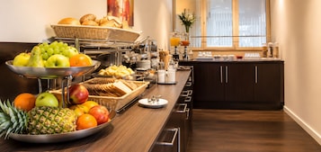 Una mesa de buffet con frutas, pan y bebidas.