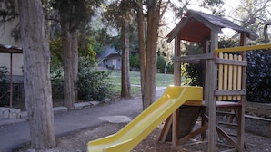A playground with a yellow slide and a wooden playhouse. - Kibbutz Beit Alfa Guest House (Gilboa)