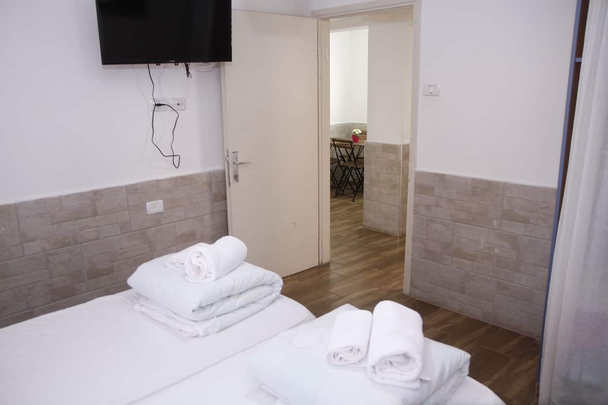 Habitación de hotel con dos camas, un televisor montado en la pared y vista al comedor.