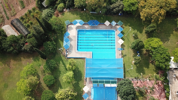 An aerial view of a swimming pool complex surrounded by greenery, with multiple lanes and covered areas. - Kibbutz Beit Alfa Guest House (Gilboa)