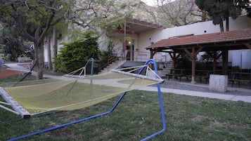 Una hamaca en un área con césped y un edificio al fondo.
