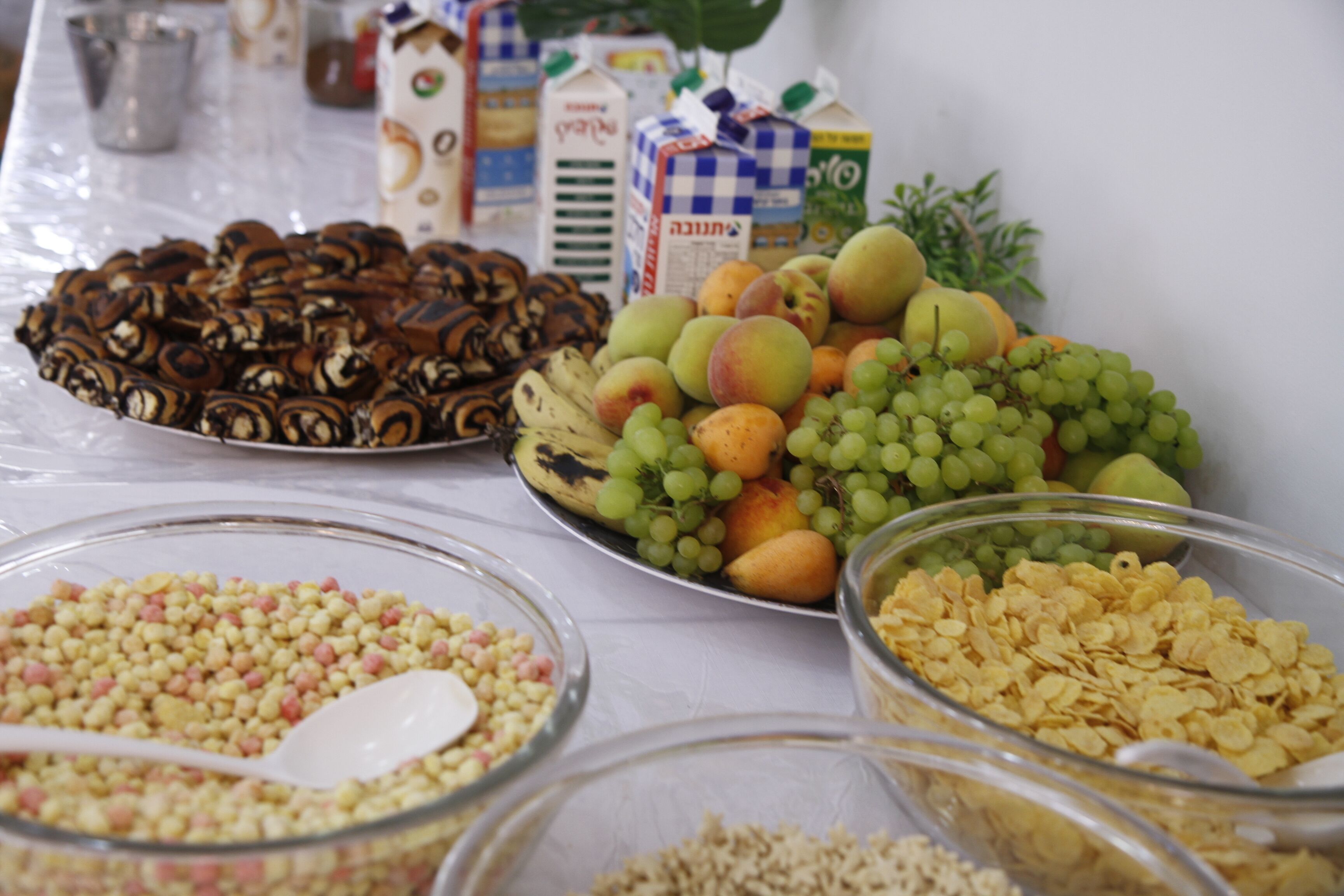 Una mesa de buffet con diversas opciones de comida, incluyendo frutas, cereales y aperitivos.