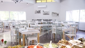 A spacious dining area with multiple tables and chairs, arranged in rows. There are various bowls of food on the tables, and the room has large windows allowing natural light. - Kibbutz Beit Alfa Guest House (Gilboa)