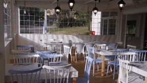 A restaurant with white and blue chairs and tables, wooden flooring, and hanging lanterns. - Kibbutz Beit Alfa Guest House (Gilboa)