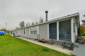 Une maison mobile de plain-pied dotée d’un porche couvert, d’une cheminée et d’une petite terrasse.