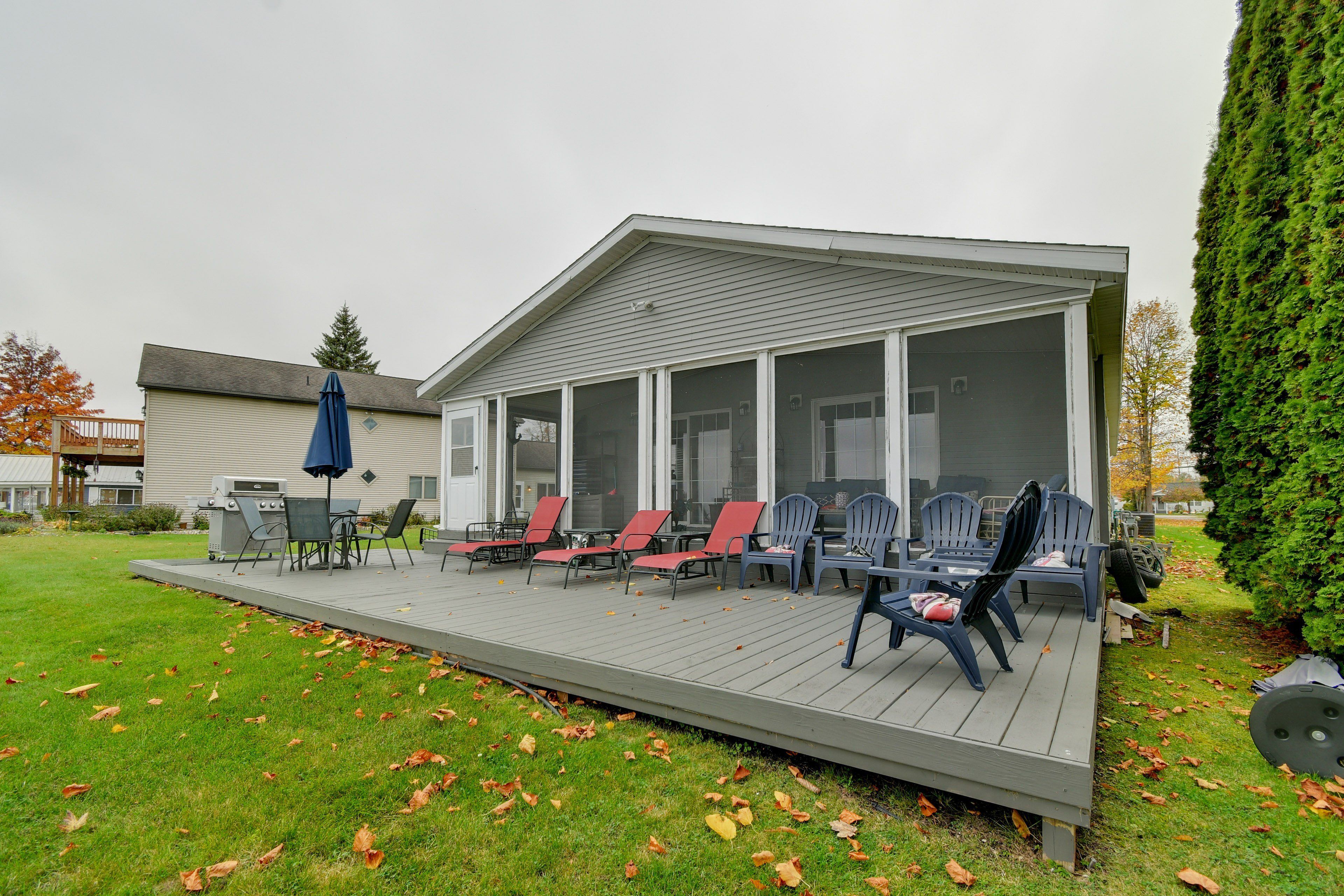 A covered outdoor deck with seating and a grill area.