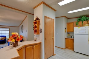 Una cocina compacta con armarios de madera, un microondas integrado y un refrigerador.