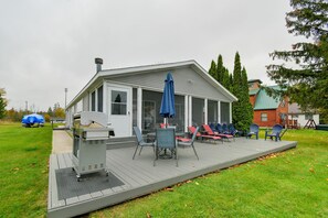 A covered outdoor deck with chairs and a grill. - Waterfront Escape on Houghton Lake: Fish & Hike! (Houghton Lake)