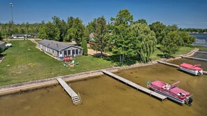 A lakeside property with a dock, a house, and a boat. - Houghton Lake Family Getaway w/ Fire Pit! (Houghton Lake)