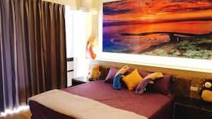 A hotel room with a large bed, a painting of a sunset, and plush toys on the bed. - Jinduohai B&B (Magong)
