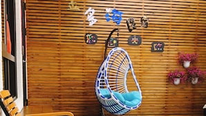 A wooden wall with hanging decorations and a hanging chair. - Jinduohai B&B (Magong)