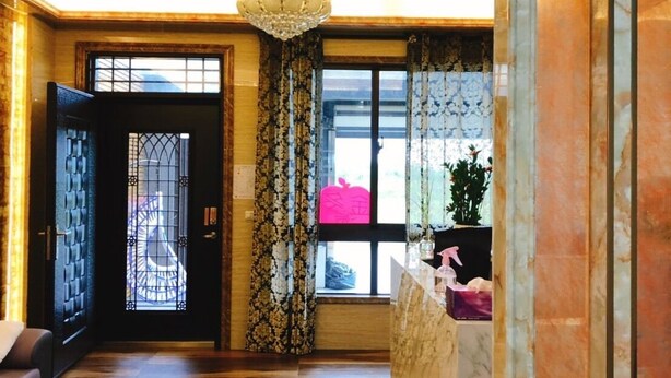 A spacious hallway with a chandelier, a reception desk, and a large window with curtains. - Jinduohai B&B (Magong)