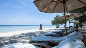 A beach with sun loungers and umbrellas, a sandy shore, and a clear view of the ocean. - The Gili Beach Resort, 4 Bedrooms Villa Gili Trawangan  - Beach Front (Gili Trawangan)
