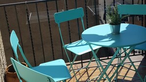 A terrace with turquoise metal chairs and a table, a potted plant, and a view of buildings in the background. - High-end, air-conditioned apartment in the heart of Banyuls (Banyuls-sur-Mer)