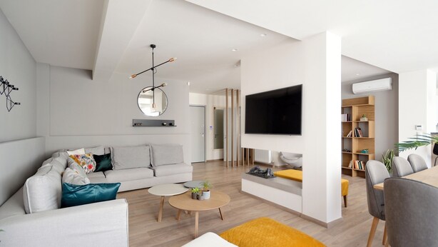 En moderne stue med en sofa, sofabord og et fjernsyn monteret på væggen.