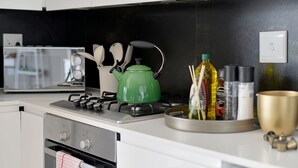 A modern kitchen with a gas stove, a green kettle, and various kitchen utensils. - Emily By Stay Amazing (Cape Town)