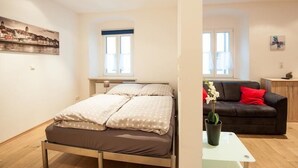 Een slaapkamer met een bed, een raam en een schilderij aan de muur.