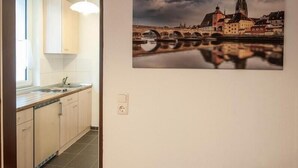 Een keuken met een raam, een gootsteen, kastjes en een wandlamp.