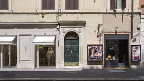 A building facade with numbered doors, a green door with a gold emblem, and storefronts with mannequins and posters. - TreasureRome Spanish Steps Terrace (Rome)