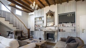 A living room with a fireplace, bookshelves, a television, and a staircase. - TreasureRome Spanish Steps Terrace (Rome)