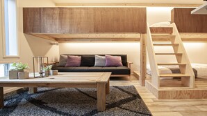 A loft-style bedroom with a bunk bed, a sofa, a coffee table, and a staircase.