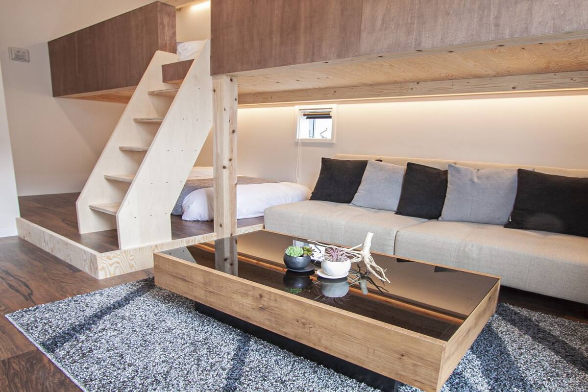 Un salon moderne avec une table basse en bois, un canapé et un escalier.