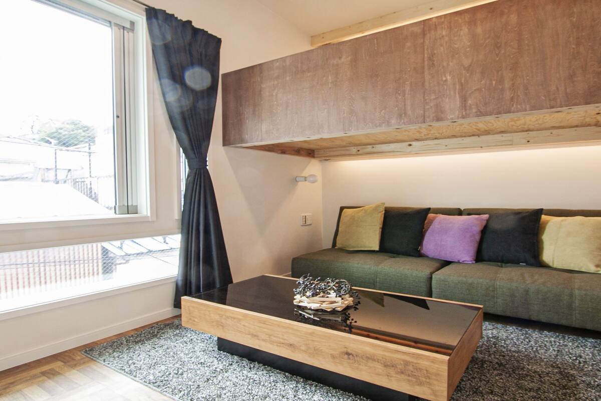 Un salon avec un canapé vert, une table basse en bois et une fenêtre avec des rideaux.