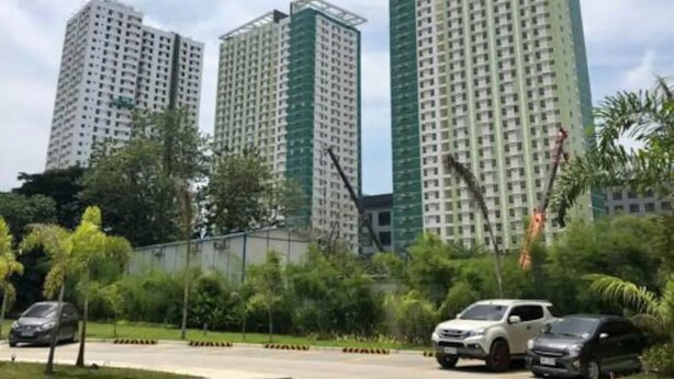 A high-rise residential building with multiple floors, surrounded by greenery and parked cars. - 27th Flr Condo1 w/WIFI @ IT Park Avida Riala Twrs (Cebu City)