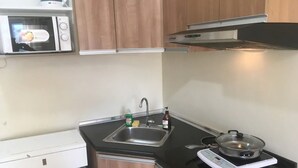 A compact kitchen with a microwave, sink, and electric stove. - 27th Flr Condo1 w/WIFI @ IT Park Avida Riala Twrs (Cebu City)
