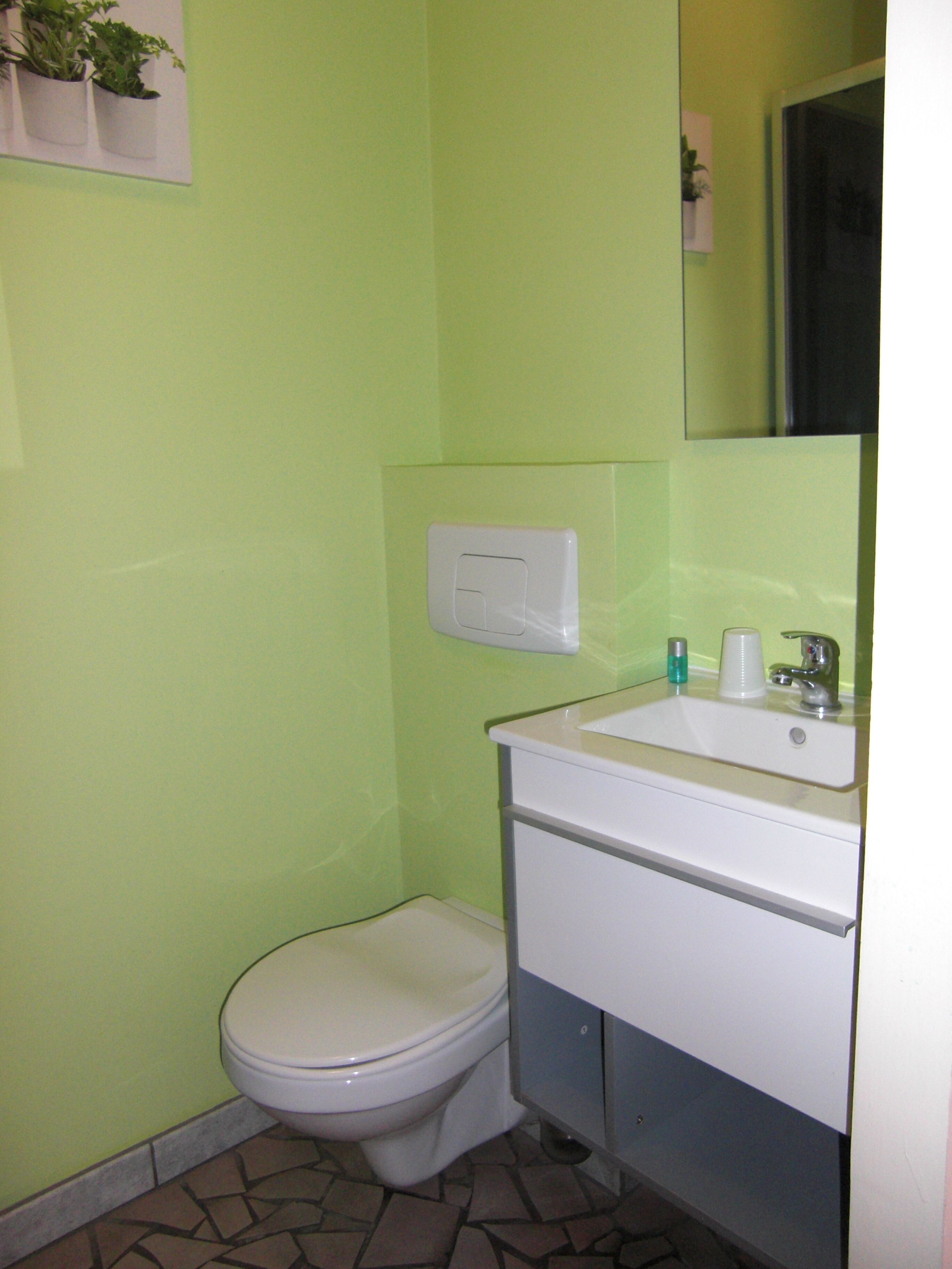 Un baño pequeño con inodoro, lavamanos y espejo.