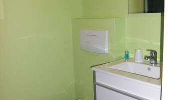 Un baño pequeño con inodoro, lavamanos y espejo.