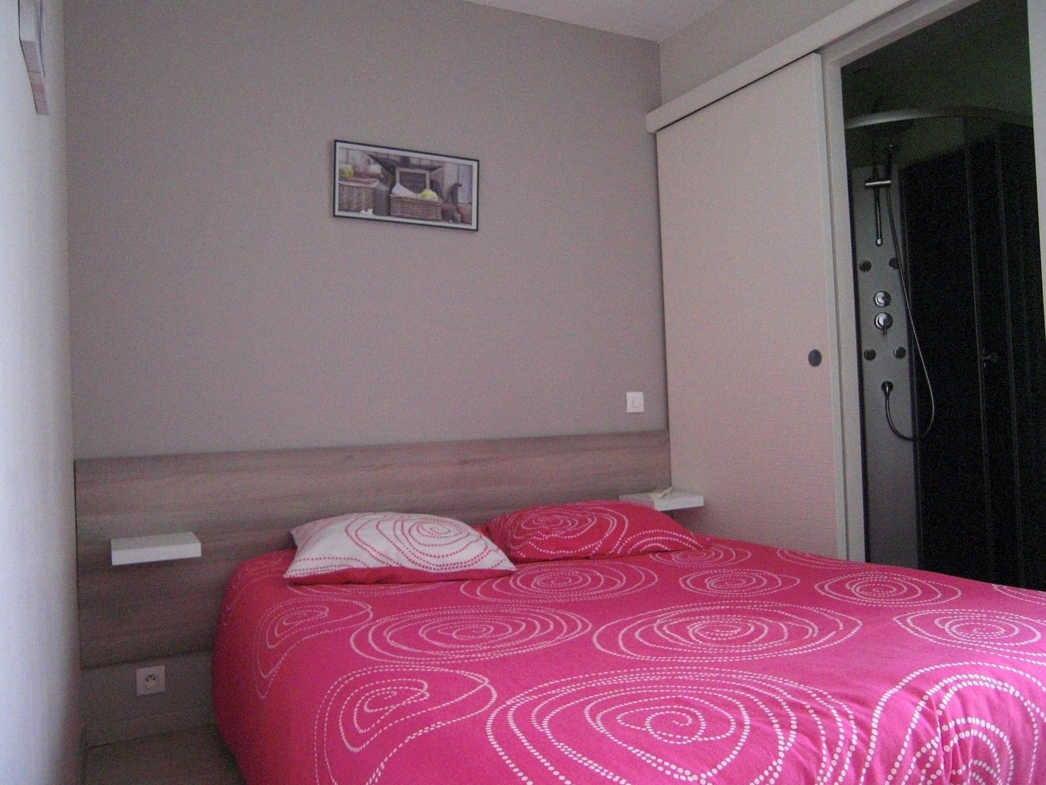 Een slaapkamer met een bed, een hoofdeinde, een klein nachtkastje en een aan de muur hangend schilderij.