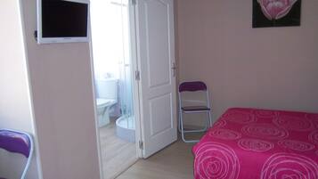 Une chambre avec deux lits, une télévision, une salle de bain visible à travers une porte ouverte et une chaise.