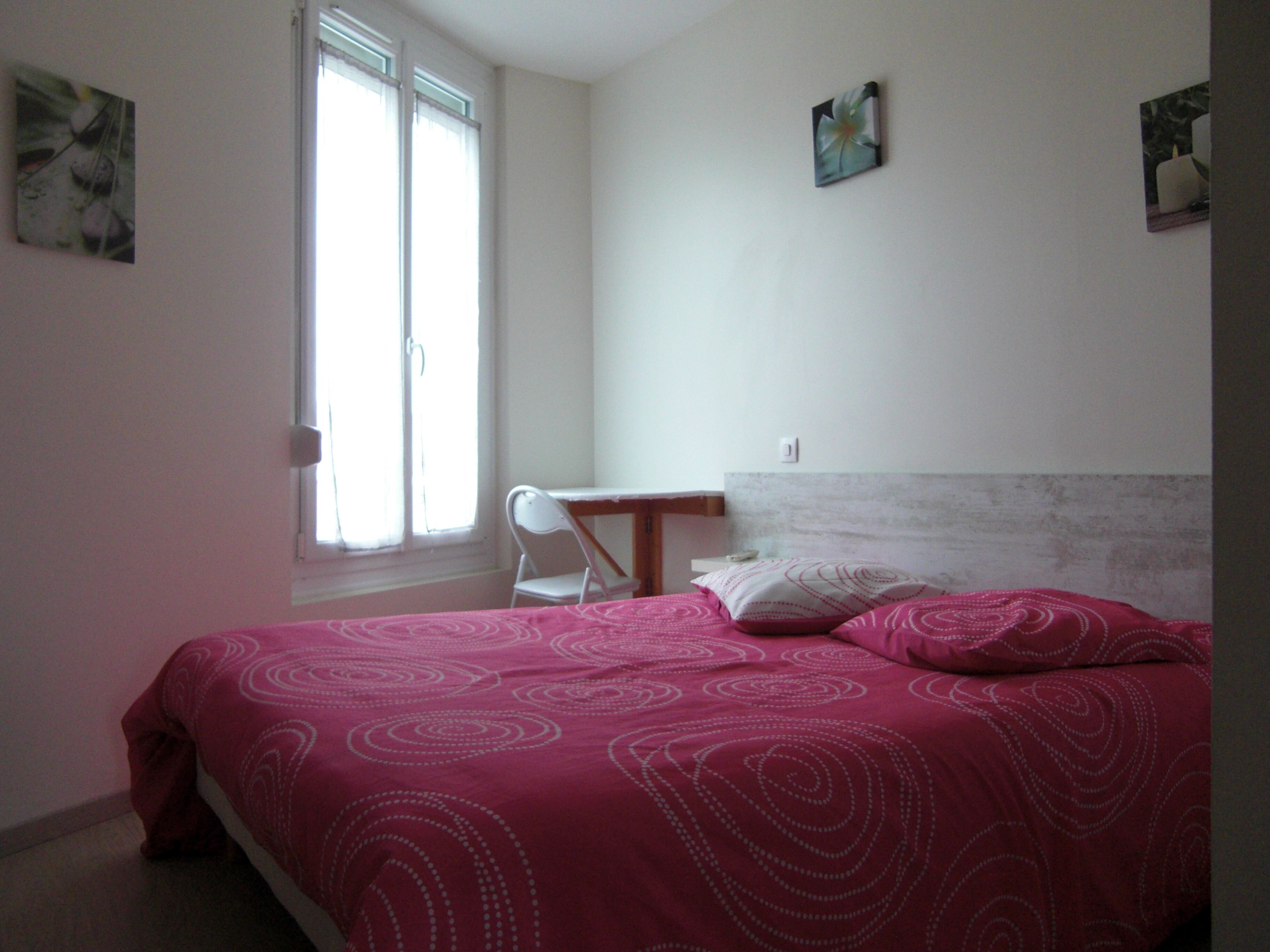 Une chambre à coucher avec un lit, une chaise, un bureau et une fenêtre.
